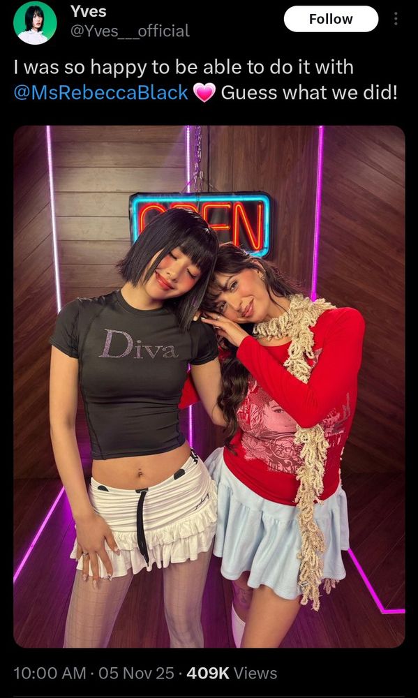 Screenshot from Yves' official Twitter. Yves kwearing a black shirt with the words Diva on the chest, a white ruffled miniskirt, and white translucent tights) is side hugging Rebecca Black (wearing a red long-sleeved T-shirt, a light blue s mini skirt and a creme knit boa around her neck.) They're very cozy.whike standing in a hallway of wood floors and walls with neon pink trim and an OPEN neon sign behind them.

The caption reads "I'm so happy to be able to do it with @MsRebeccaBlack. Followed by a pink heart emoji. Guess what we did!"