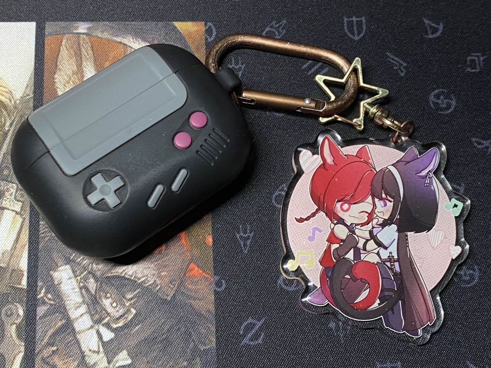 Similar to the first image, but in chibi form as an acrylic charm! (Charm by @sachayacomms.bsky.social) The charm is attached to my airpod case.