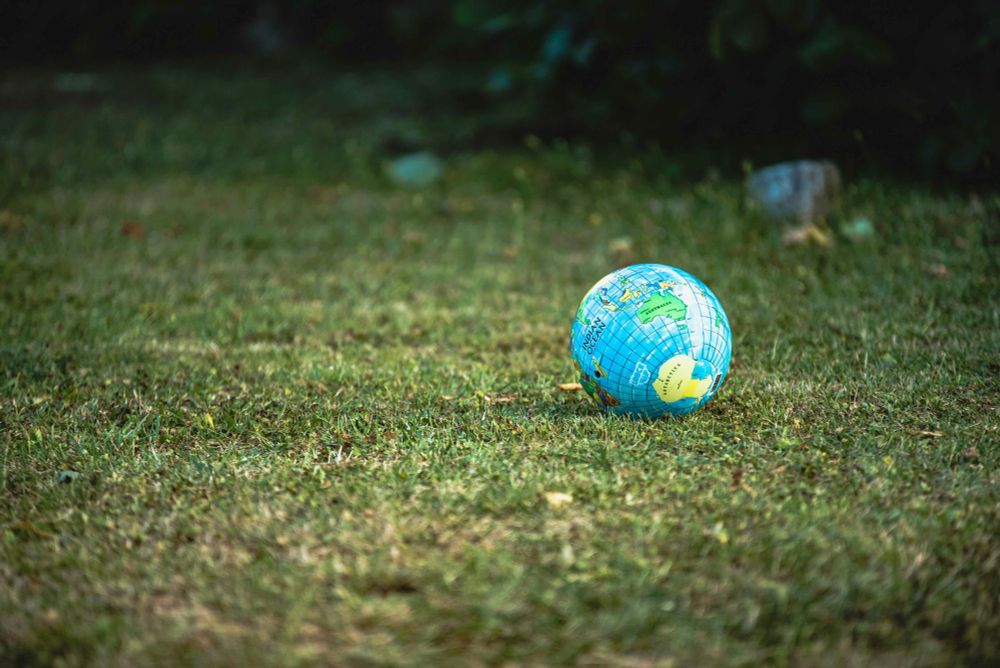 Small inflatable globe resting on green grass with green grass in the background
