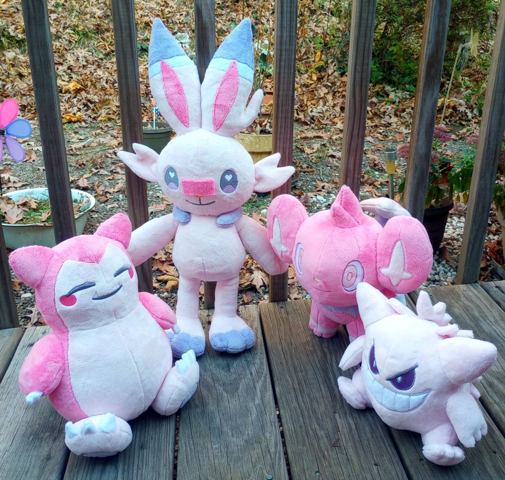 Four handmade Pokemon plushies reimagined in pink colors.  From left to right: Snorlax, Scorbunny, Shinx, and Gengar.