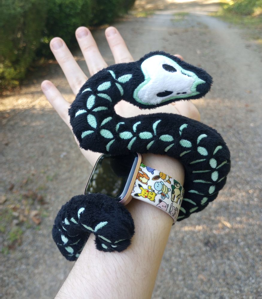 A handmade skeleton snake plushies wrapped around my hand.