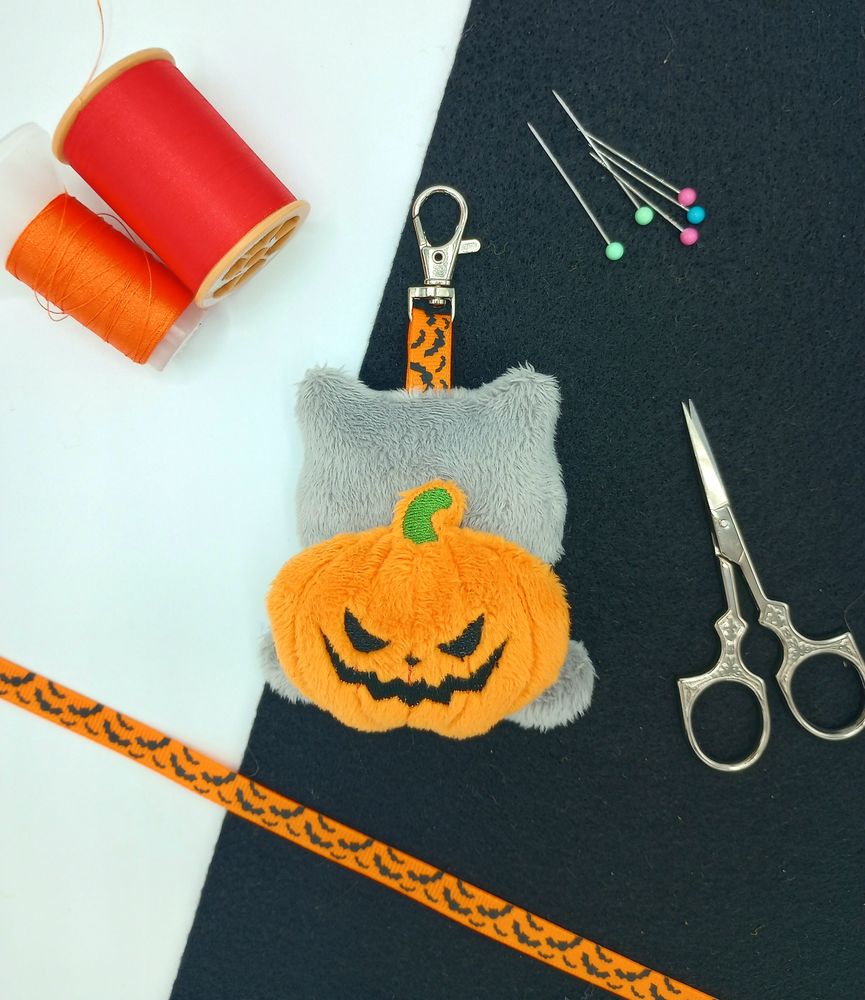 A handmade Pumpkin Bulbasaur plushie keychain from Pokemon.  Shown from the back to see its jack-o'-lantern bulb.