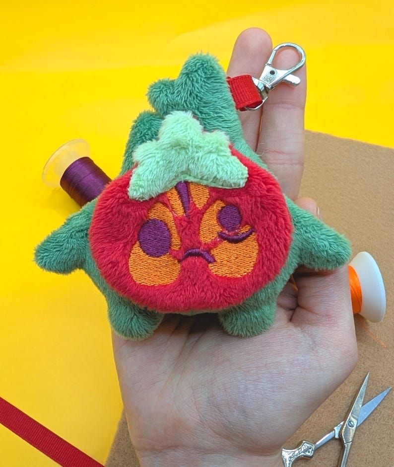 A handmade Tomato Korok plushie keychain from the Legend of Zelda.