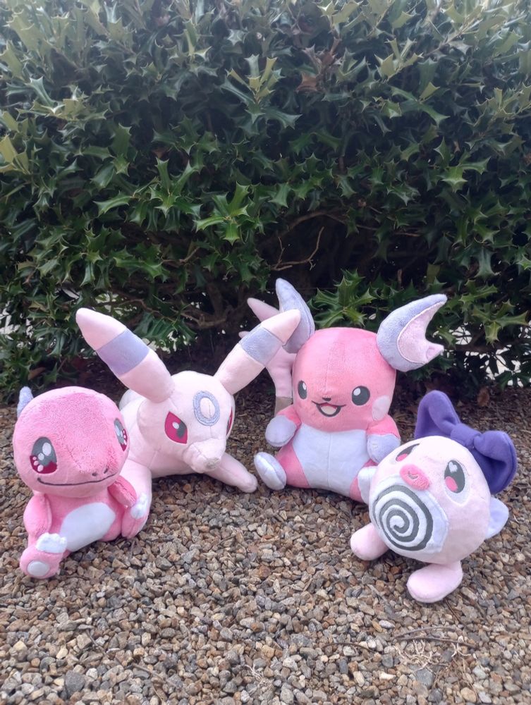 Four handmade Pokemon plushies reimagined in pink colors.  From left to right: Charmander, Umbreon, Raichu, Poliwag.