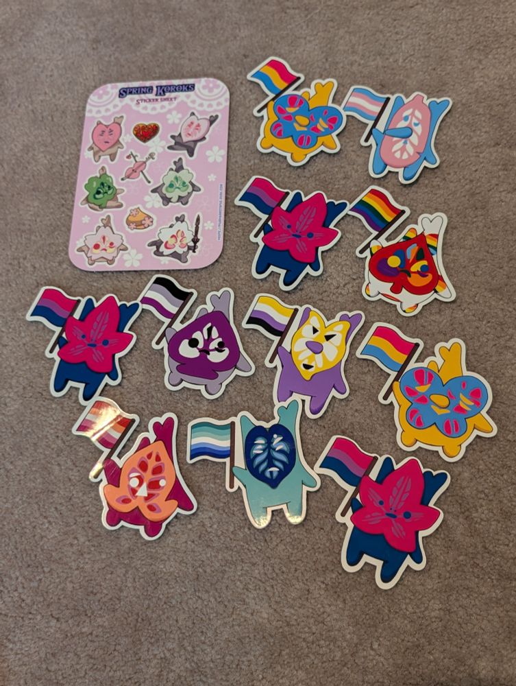 A group of handmade Korok vinyl stickers from the Legend of Zelda.  Includes Spring and Pride flag designs.