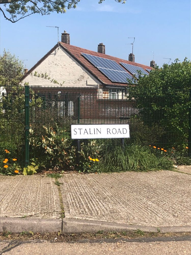 A street sign reading ‘Stalin Road’ with the start of a row of houses in the background. 