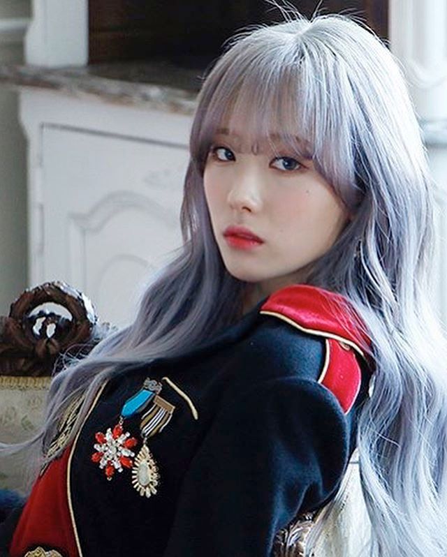 Luda from WJSN during a photoshoot for the song Dreams Come True. She is wearing a uniform-style outfit and has light gray hair.