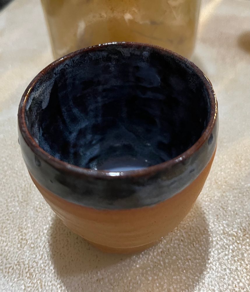 Brown pottery tea cup with the interior and top half-inch of exterior dyed a rich dark blue reminiscent of the night sky