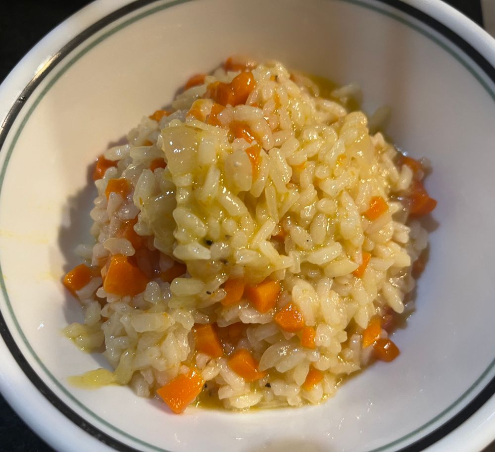 Glistening grains of rice and diced carrot, a little yellow from vegetable stock, piled in a white bowl.