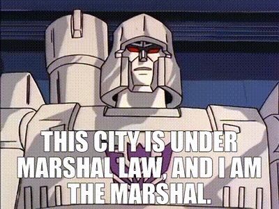 Megatron, a large, evil, humanoid robot, states at the camera and proclaims, 