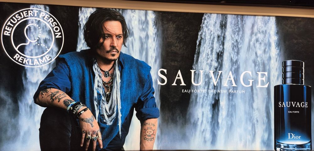 Man sieht Johnny Depp, der für einen Herrenduft wirbt und auf dem Plakat ist ein Hinweis, dass sein Abbild retuschiert worden ist.