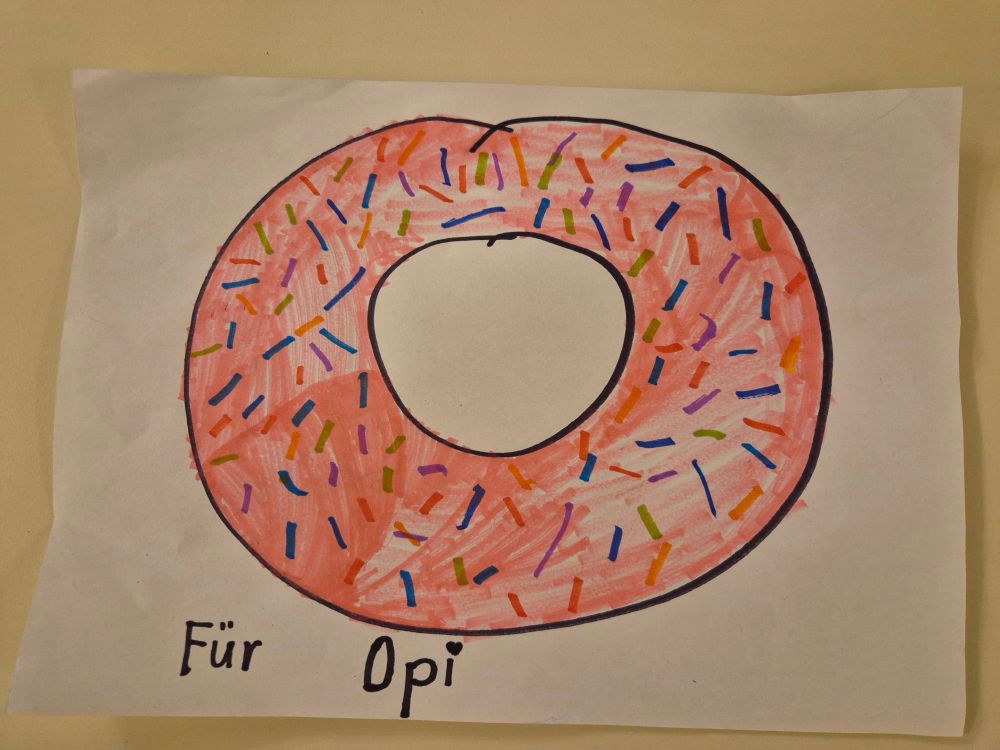Man sieht die Zeichnung von einem Doughnut mit bunten Streuseln und da steht "Für Opi"