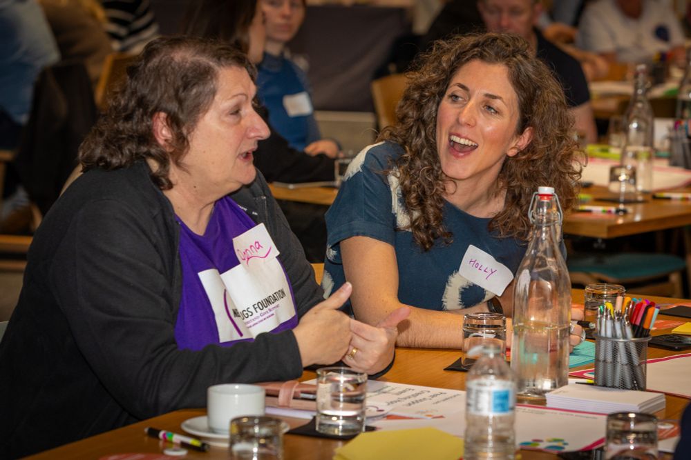 Two event participants sitting at a table in conversation.