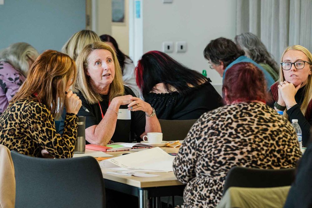 A group of event participants sitting around a table sharing ideas and taking notes.