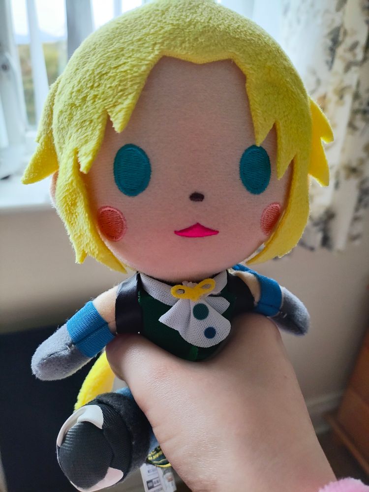A hand grasping a small plush of Zidane from FF9. It has an incredibly head empty expression.