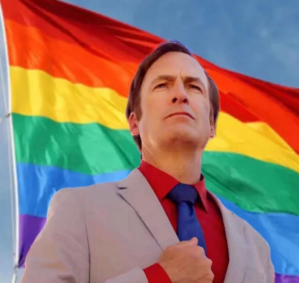Peak, totally unaltered image of Saul Goodman standing in front of the pride flag like a boss.