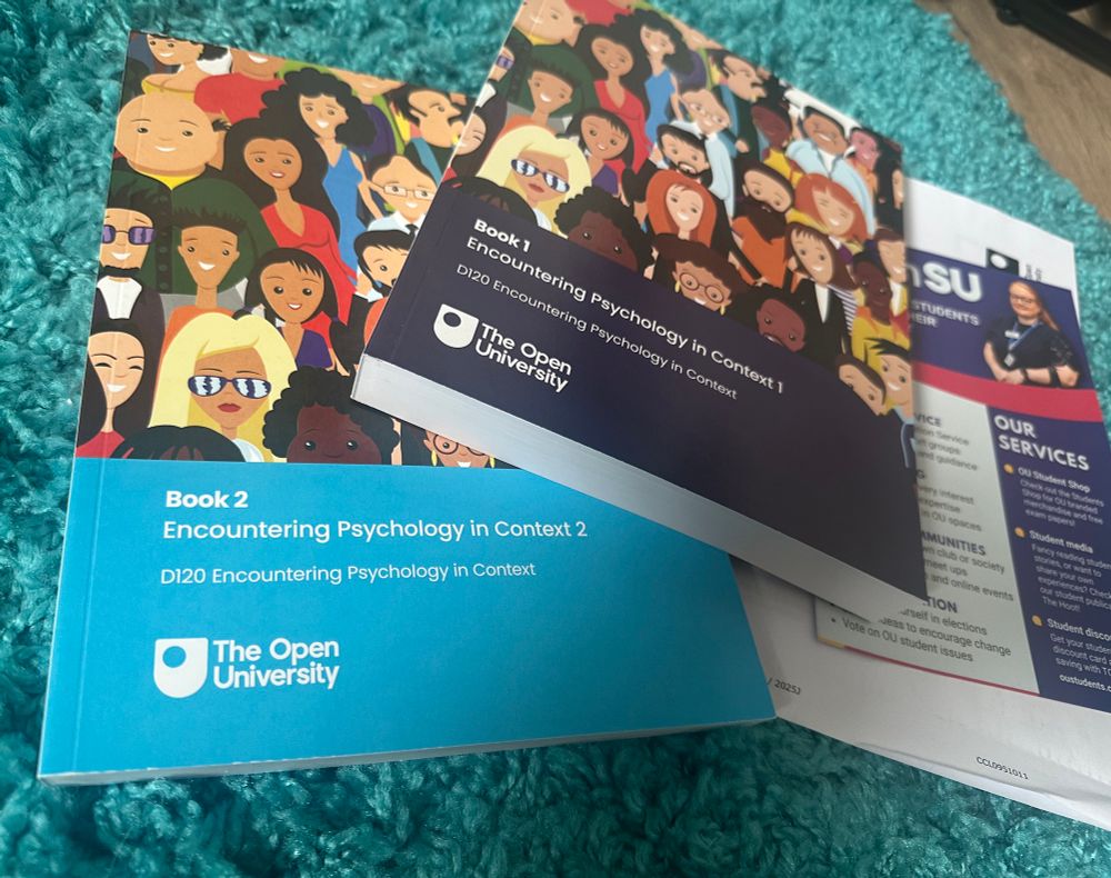 Two large text books from The Open University. Both have cartoon drawings of people on the covers, one is a dark blue, the other is light blue. The titles are “Encountering Psychology in Context” books 1 and 2