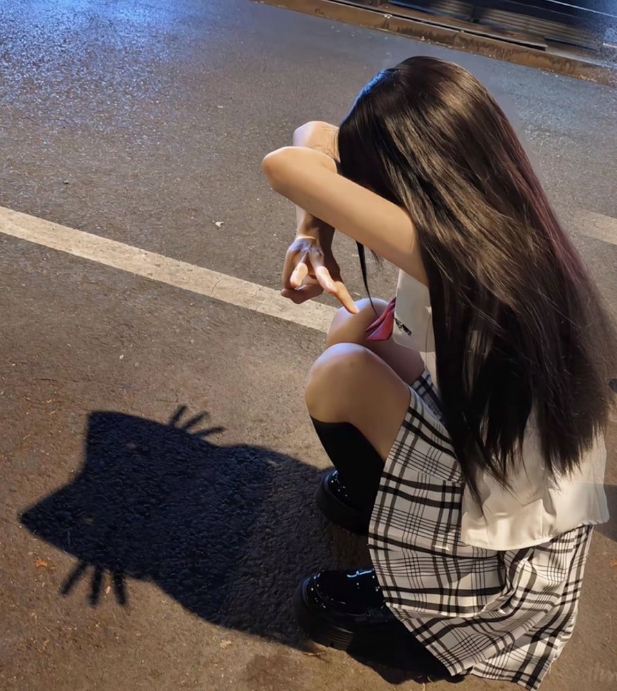 Girl crouching on the street, her shadow looks like a stylized cat