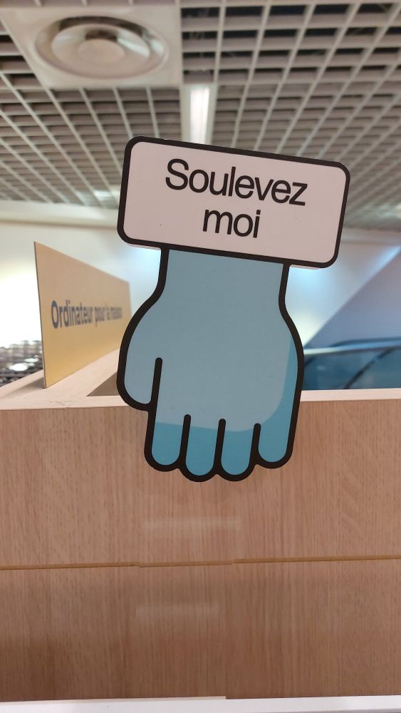 Visuel de rayonnage sur lequel est écrit "soulevez moi"