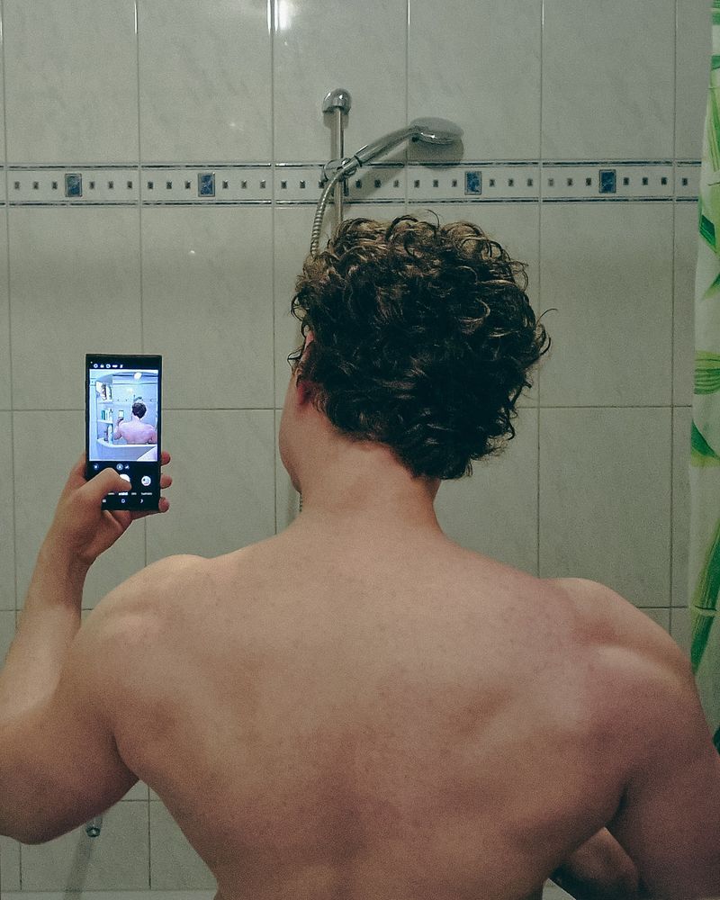 Muscular upper back in mirror selfie