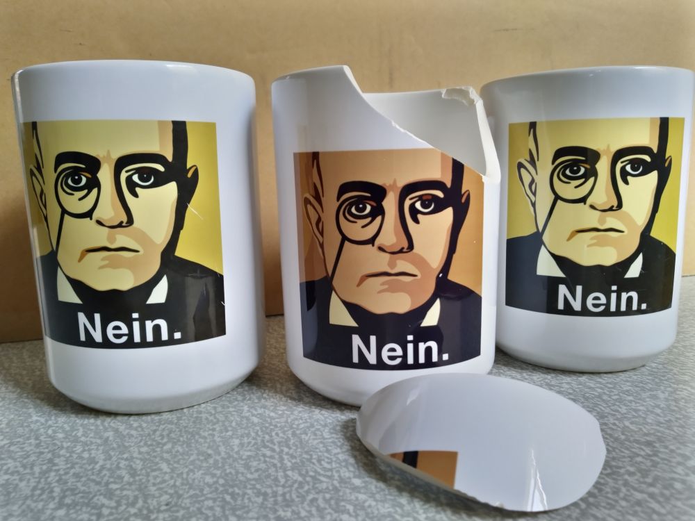 Three mugs that say Nein. One of them is broken.