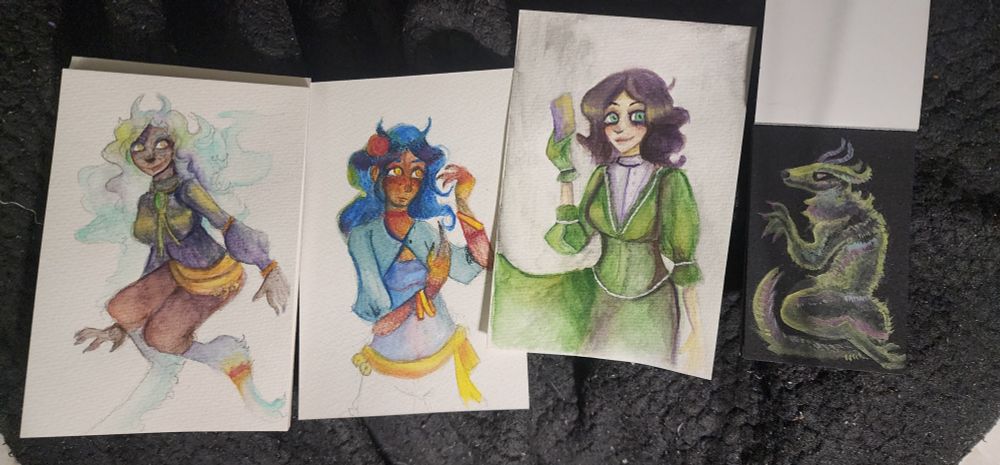 A series of watercolor paintings. One depicts a girl with dog like feet, two depict women in bright colors and the last is a picture of a dog creature with horns.
