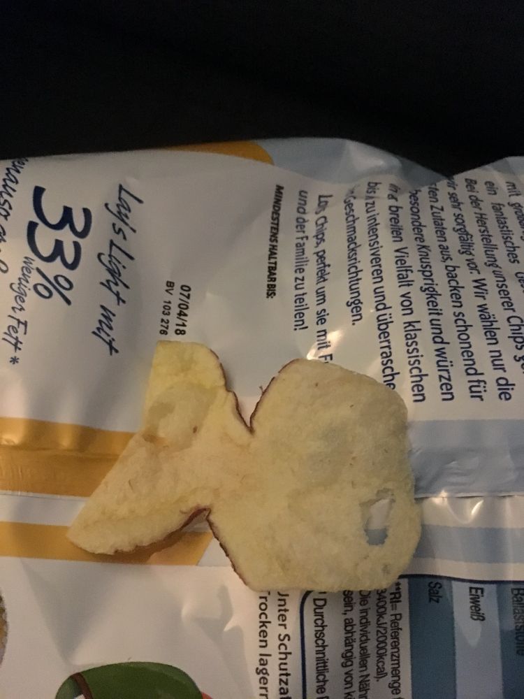 Fischförmiges Kartoffelchip auf einer Chipstüte
