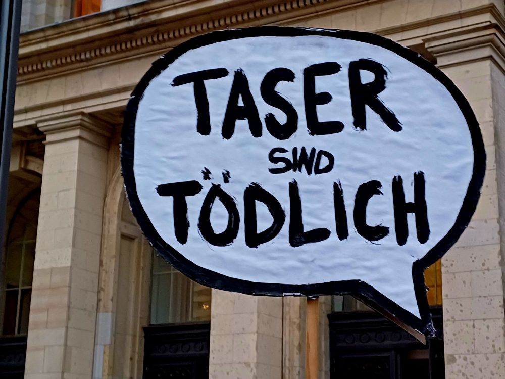 Sprechblase als Hochhaltepappe mit Aufschrift "Taser sind tödlich"
