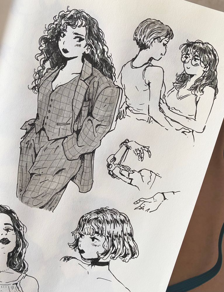 Ink drawings on a sketchbook page : a woman wearing a suit, a lesbian couple sharing a cute moment, a cute blasé girl with a blonde curly bobcut ; also quick inks of a metal/cyber arm