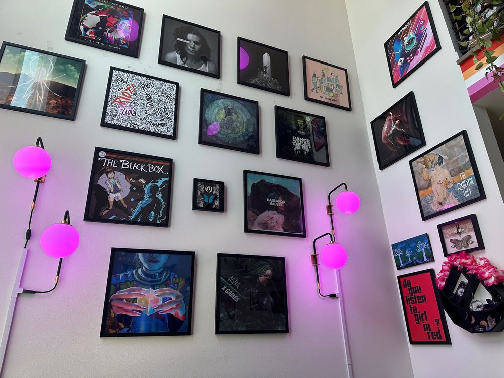 The wall of a home with a high loft ceiling, which is covered with album art (PVRIS, Anamanaguchi, girl in red, etc)