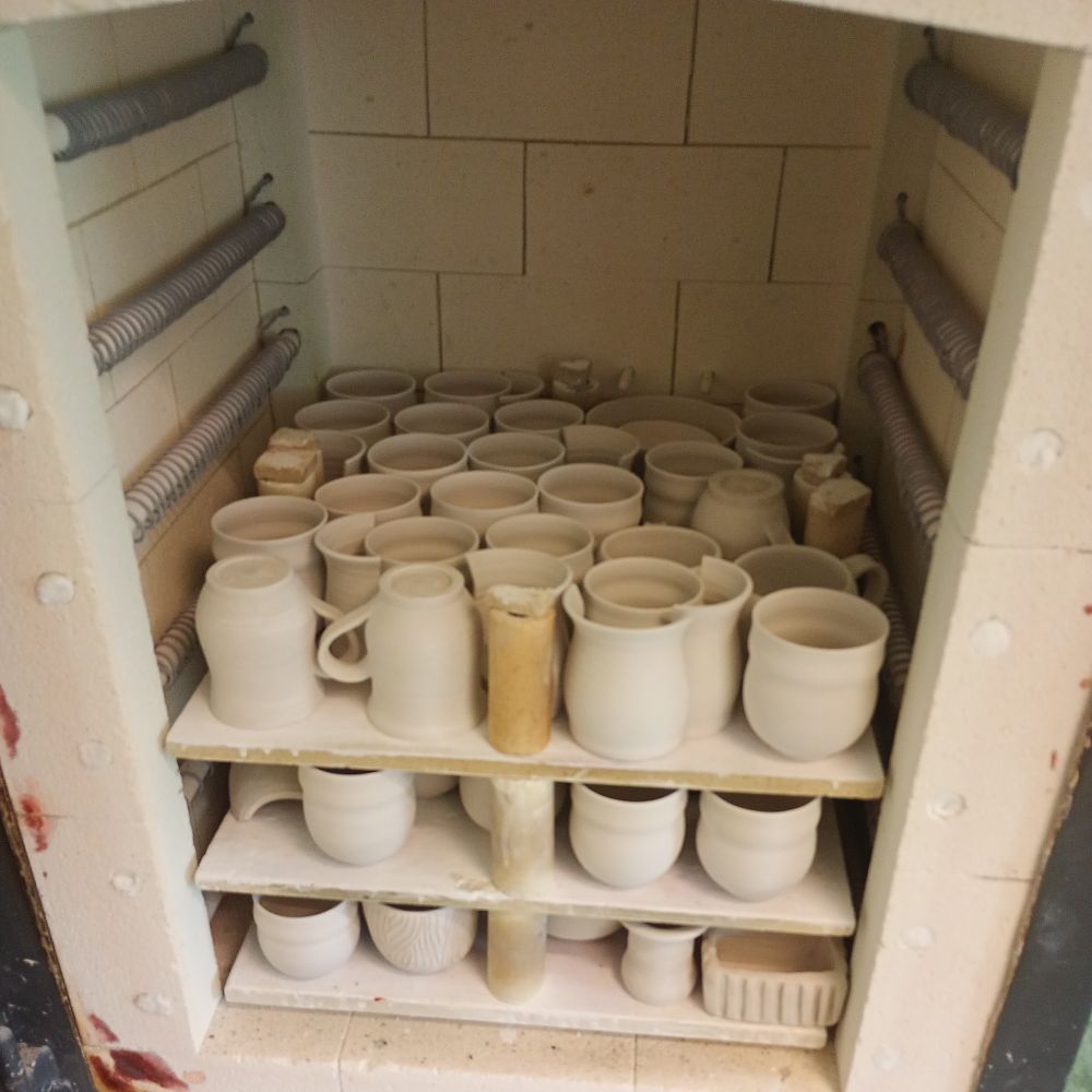 A somewhat newer electric kiln, densely stacked with unfired stoneware cups