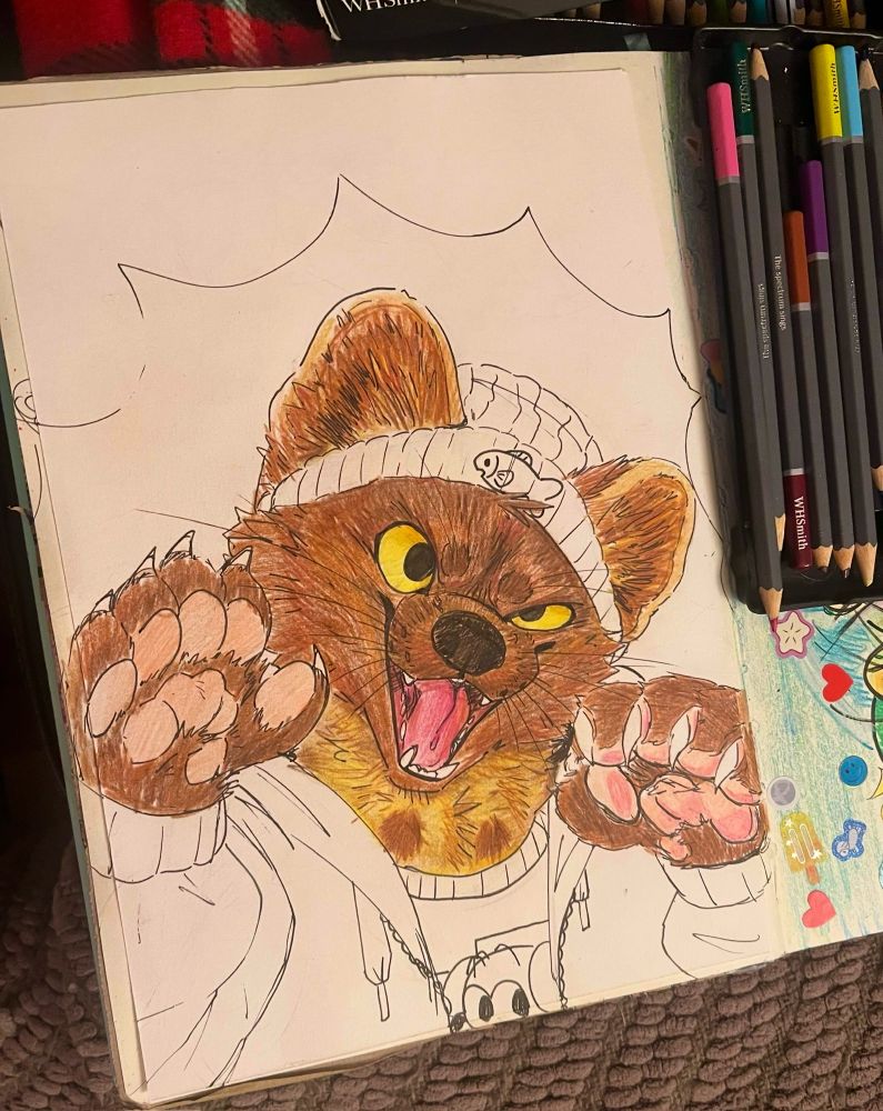 A picture of a sketchbook, there is a half finished drawing of a pine marten character with a wide loop sided open mouth smirk. He has his paws up with claws and is wearing a beanie and hoodie, the clothes are not coloured in.