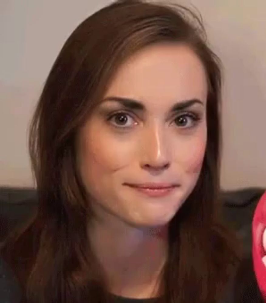 a close up of a woman 's face making a funny face while sitting on a couch .