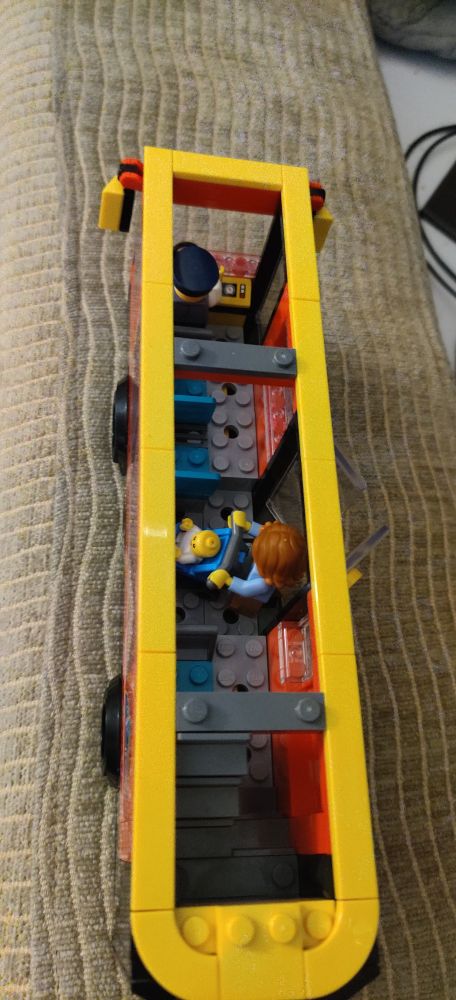 Look inside of the bus, a lady is boarding with a pram, and the bus driver is sat up front