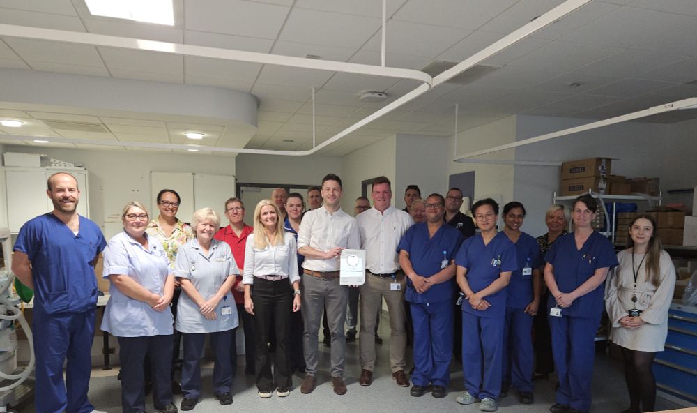 Large group of people holding award, some in surgical scrubs