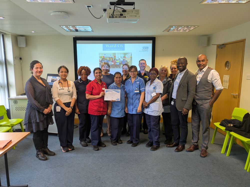 Group of staff standing with award certificate, some in nursing uniforms