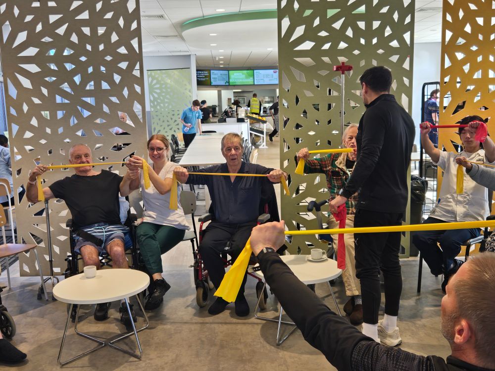 Older patients taking part in chair-based exercise with therapists