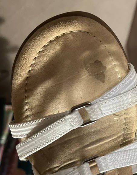 The bottom of a sandal with a small smudge stain on it. The shape is unrecognizable.