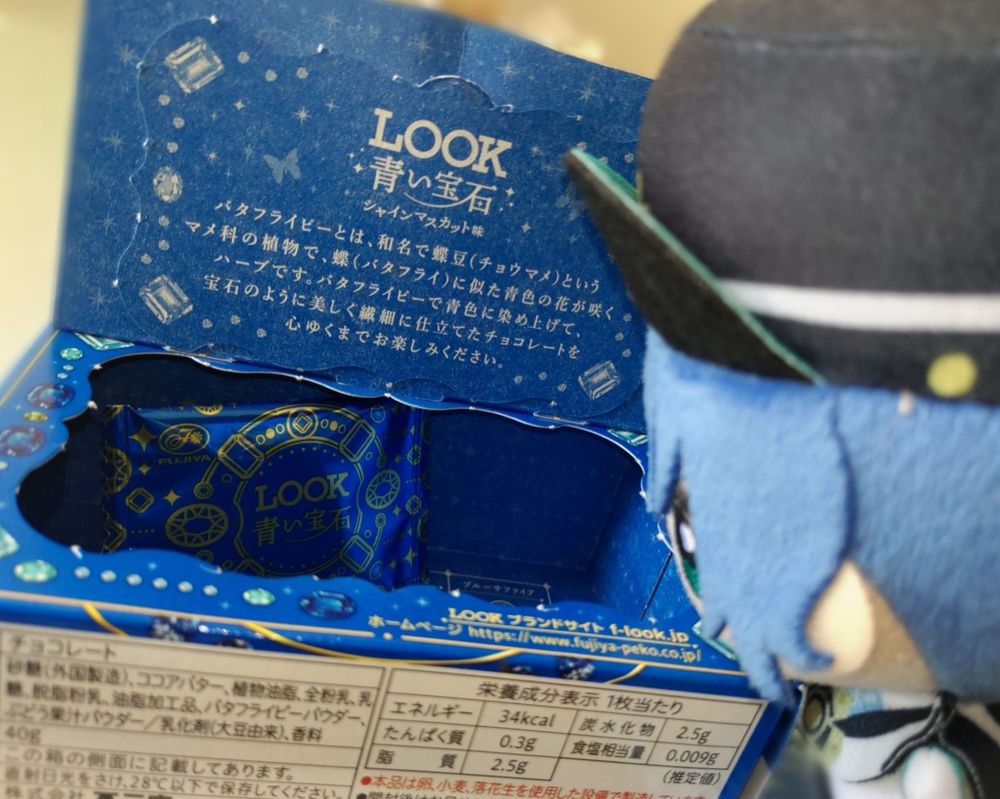 右側にちび秀くん、LOOK青い宝石チョコの箱の中、左側に個包装が1つあり見つめている様子。
