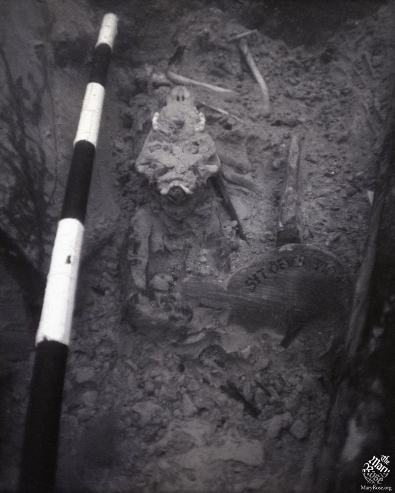 Hatch's skull on the seabed, lying upside down with his teeth showing between a striped scale pole and a flagon lid.