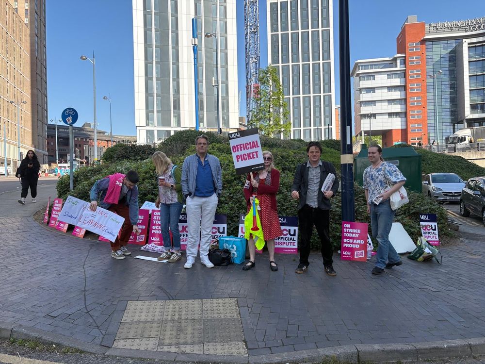 Workers on a picket with placards and supporters visiting