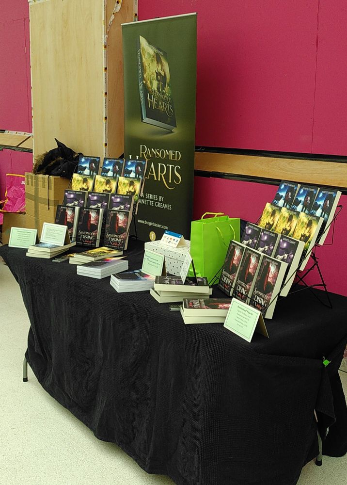A book stall with Ransomed Hearts books on sale. A table with a black cloth, two display stands, books on the table, price and information cards, a pull up banner. 