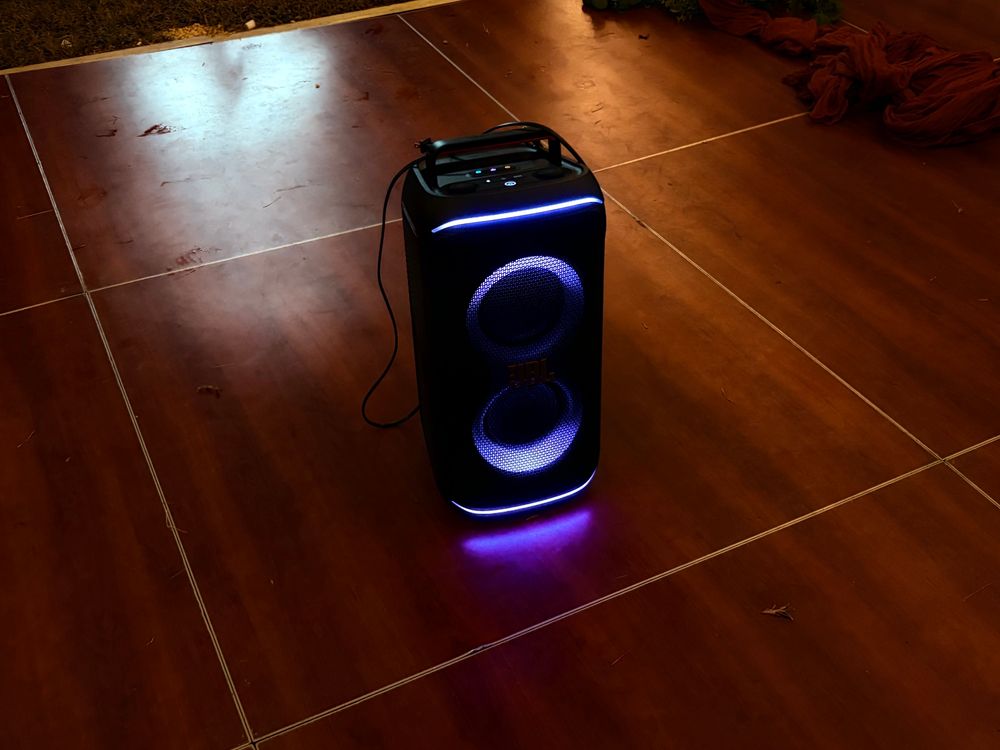 A party speaker lit up in purple on a dance floor