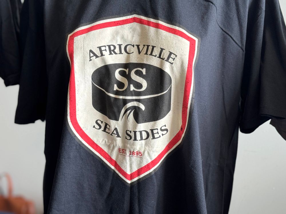Dark blue vintage looking shirt with historic Africville SS Sea Sides EST 1895 logo. The logo is cream, red and black. There is a hockey puck in the centre. 