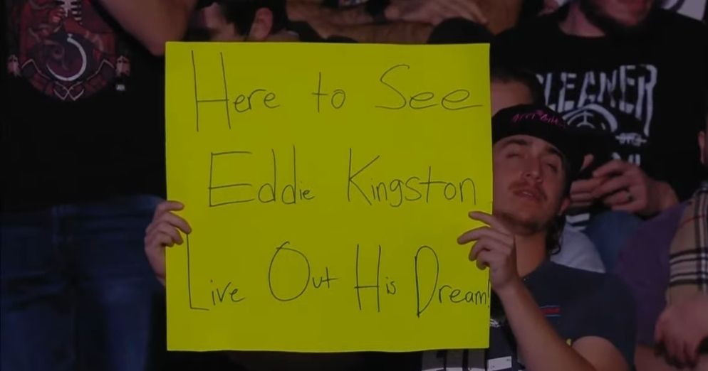 Fan holding a "Here to see Eddie Kingston live out his dream" sign while Eddie is breaking down in the ring after beating one of his heroes, Jun Akiyama