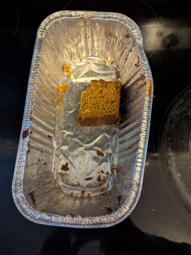 A tin of pumpkin bread. There is half a slice left 
