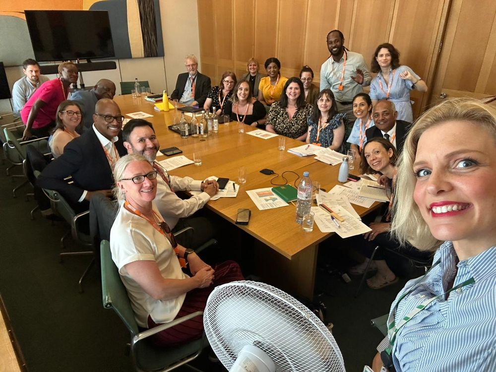 A selfie photo taken by Samantha Niblett with Samantha (and an electric fan, given the hot weather this week!) in foreground and a group of around 20 people, incl Prof Fenton and BSA CEO Hannah Russell smiling around a large wooden table.