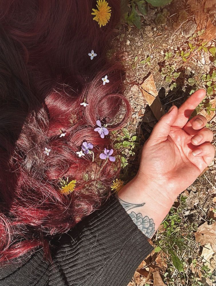 FTR’s laying on the forest floor with only her hand and hair visible. Her hair has dandelions, azure bluets and violets in it 