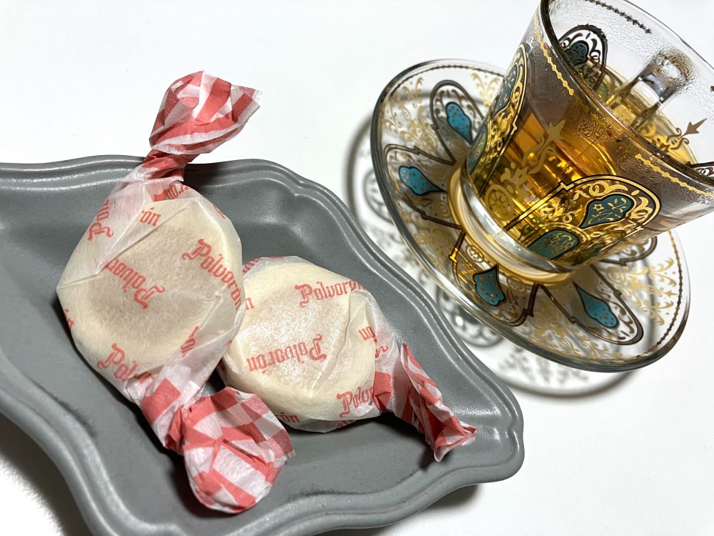 小皿に乗せたポルボロン（クレマカタラーナ味）と紅茶の写真。