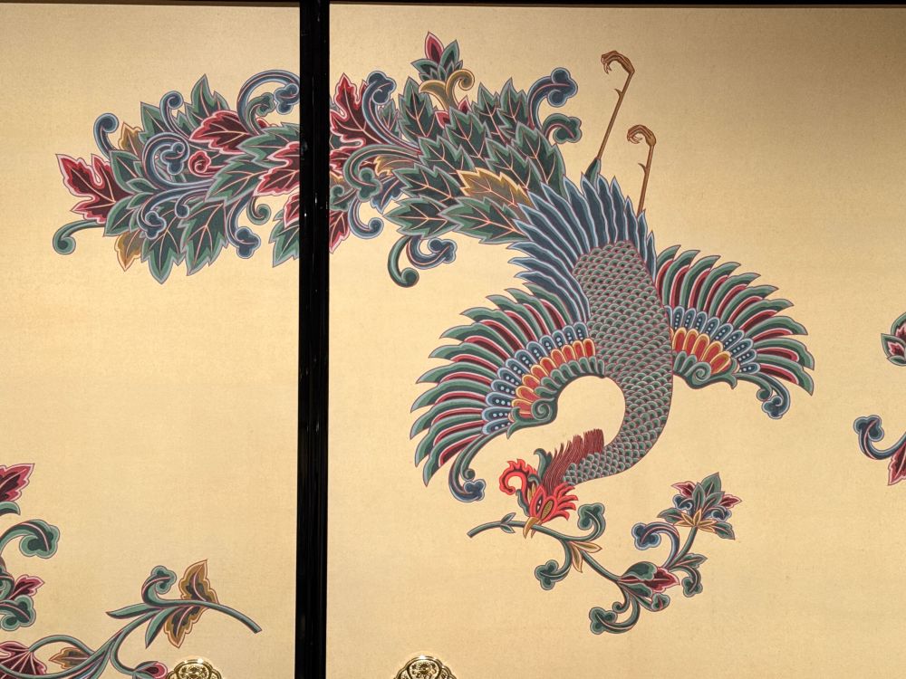 小泉淳作《鳳凰》東大寺所蔵 部分
染織か工芸品の図案にありそうな、装飾的に描かれた鳳凰。花の咲いた枝を咥えている